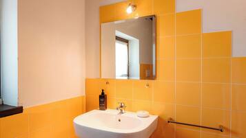 Un baño con lavamanos blanco, un espejo y azulejos anaranjados.