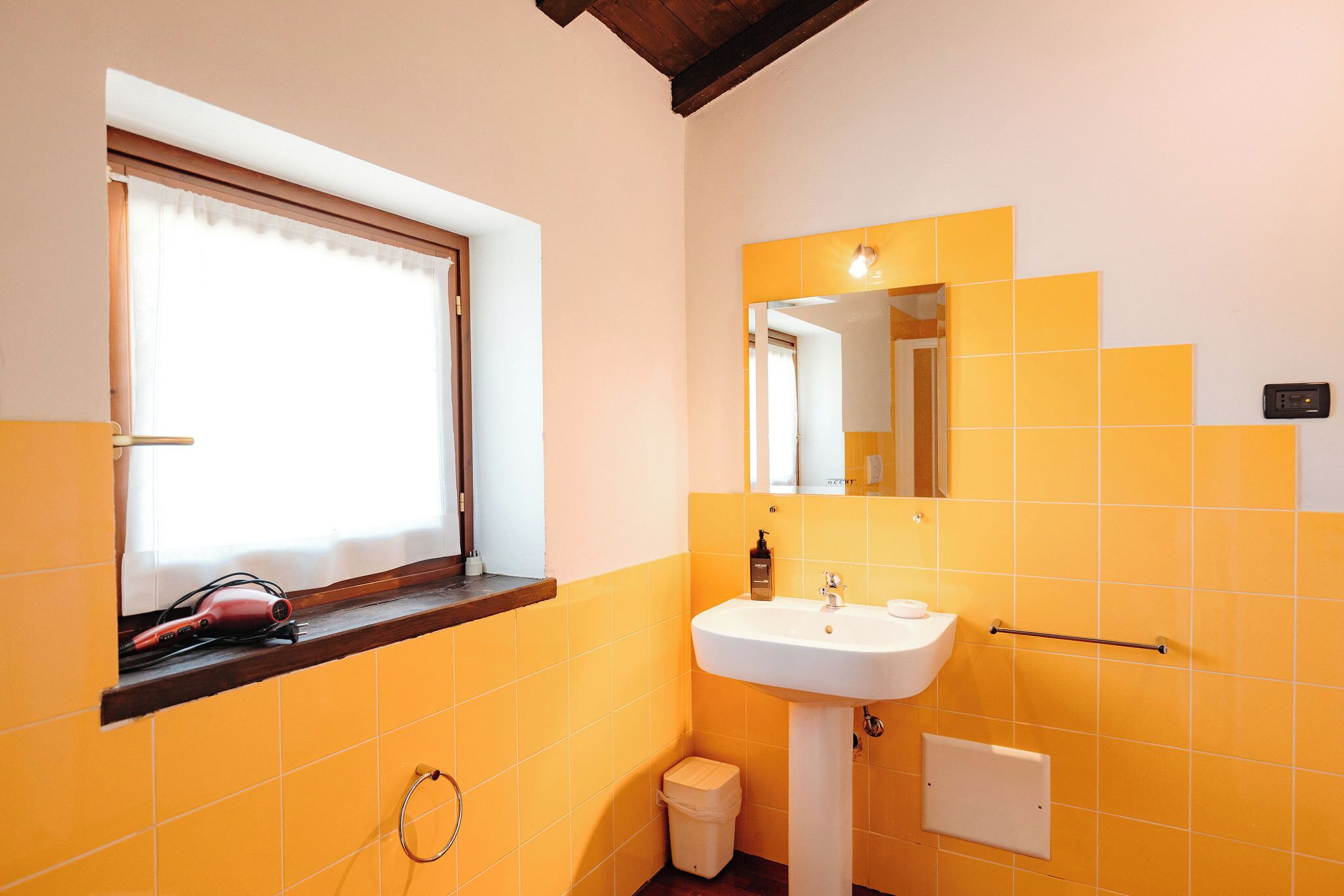 A bathroom with a window, a sink, a mirror, and a towel rack.
