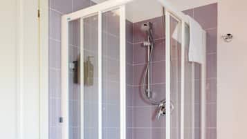 Una doccia a pavimento con porta in vetro, soffione e doccetta manuale.