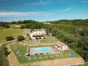 A large villa with a swimming pool, surrounded by a well-maintained lawn and several lounge chairs. - Tenuta Bellingeri - Locanda del Barco (SANT AGATA FOSSILI)