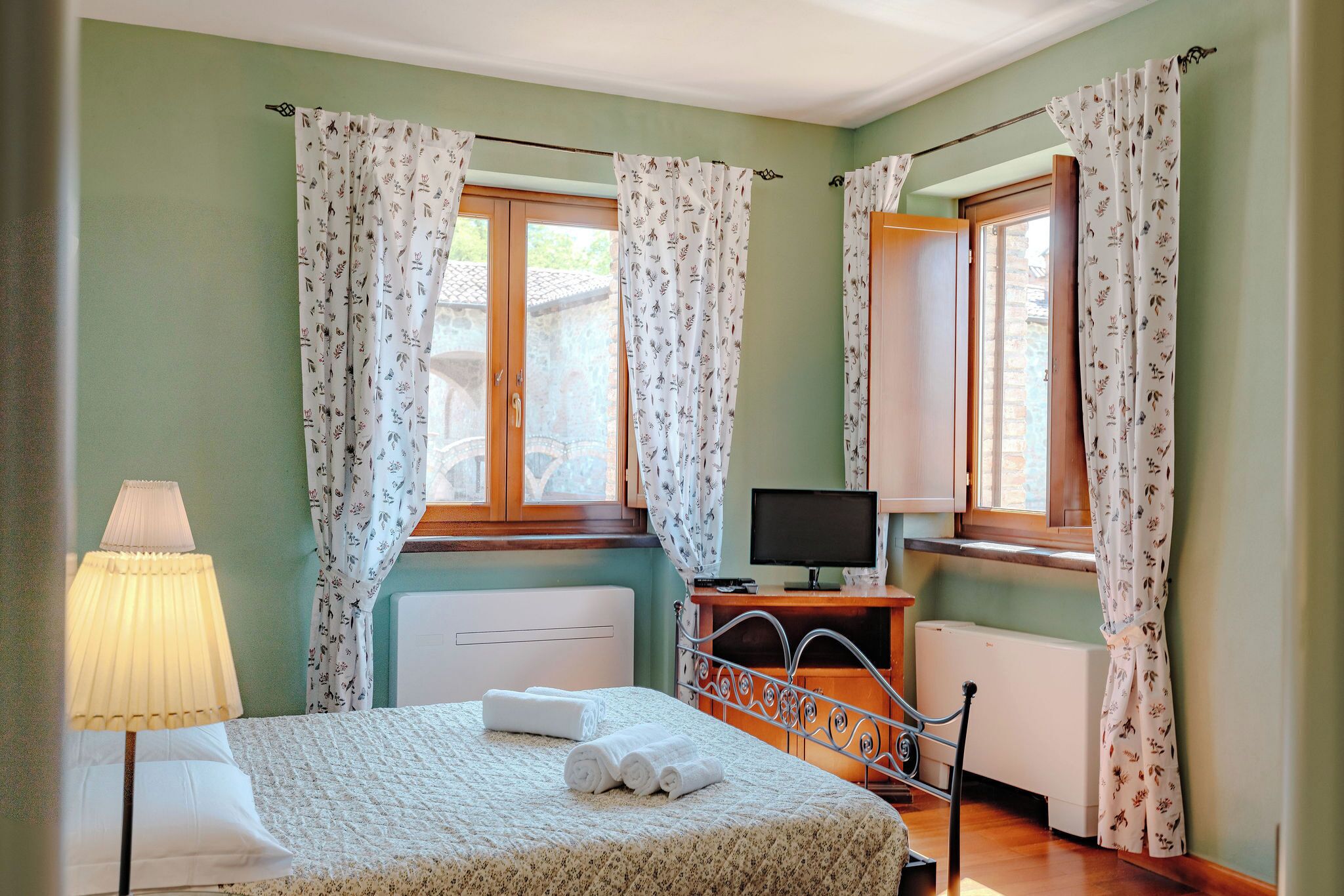 A bedroom with a bed, a TV, and a desk.