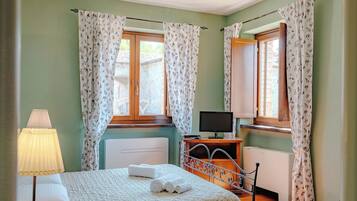 A bedroom with a bed, a TV, and a desk.