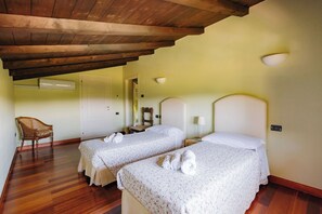 Habitación con dos camas, una silla y techo de madera.