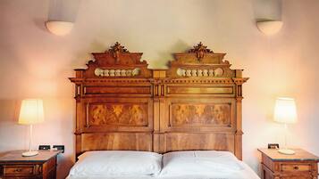 Un lit avec une tête de lit en bois, deux tables de chevet avec des lampes et une petite table de nuit avec une lampe.