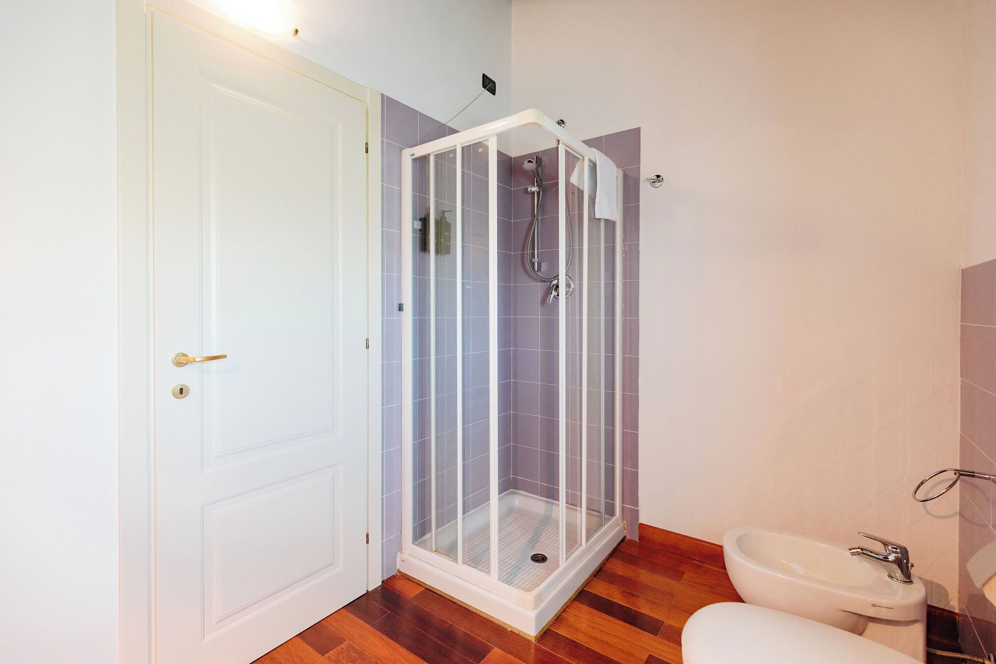A bathroom with a shower enclosure, a toilet, and a sink.