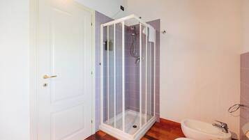 A bathroom with a shower enclosure, a toilet, and a sink.