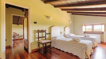 Una habitación con dos camas, piso de madera, una silla y una ventana.