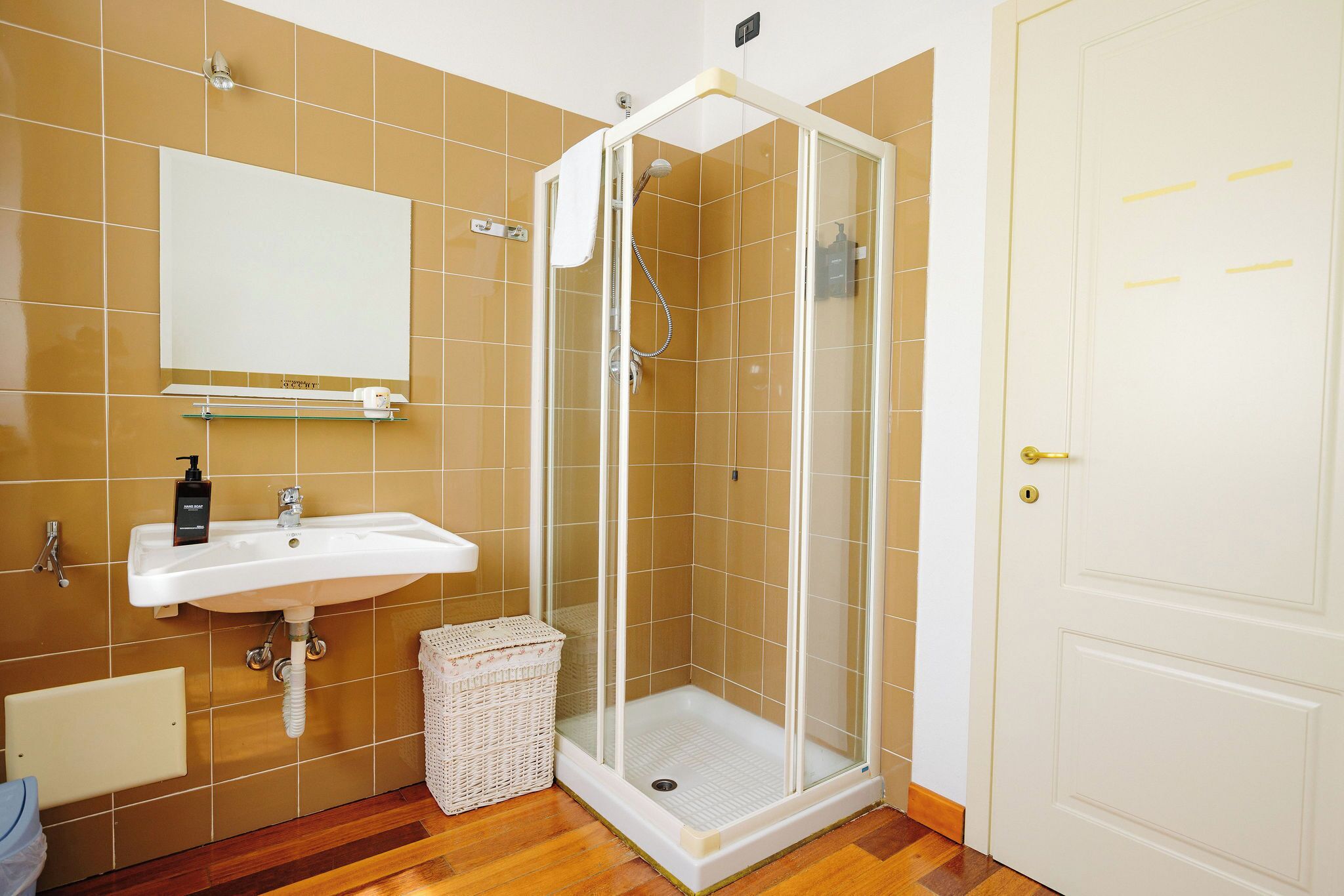 Un baño con ducha acristalada, lavabo y espejo.
