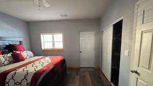 Un dormitorio con cama, ventana, puerta y armario.
