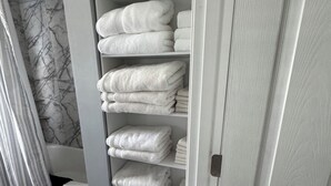 A bathroom with a marble wall, a white towel rack with neatly folded towels, and a closed door.