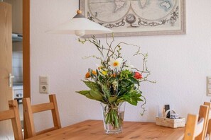 A dining table with a clear glass vase containing flowers, wooden chairs, and a wall-mounted globe. - Holiday apartment with 1 bedroom (Meersburg)