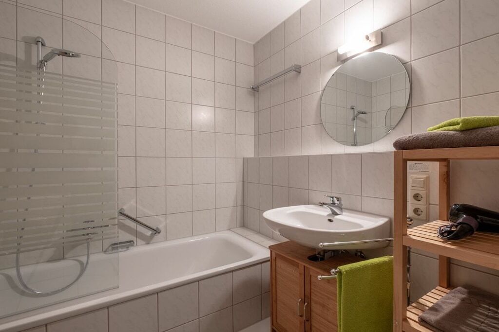 Ein modernes Badezimmer mit einer Badewanne, einem Waschbecken und einem Spiegel.