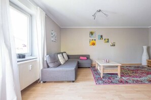 A living room with a grey sofa, a small table, and a colorful rug. - Holiday apartment with 1 bedroom (Meersburg)