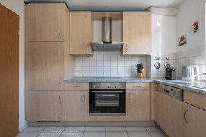A kitchen with wooden cabinets, a built-in oven, and a stainless steel range hood. - Holiday apartment with 1 bedroom (Meersburg)
