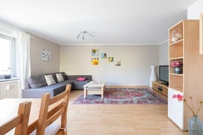 Ein Wohnzimmer mit Sofa, Couchtisch, Fernseher und Bücherregal.
