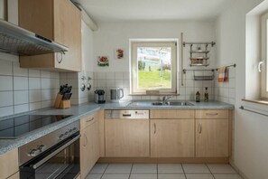 Une cuisine compacte équipée d’un lave-vaisselle, d’une cuisinière et d’une fenêtre donnant sur l’extérieur.
