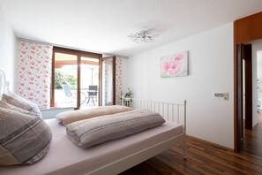 Un dormitori amb un llit, una finestra amb cortines, una làmpada al sostre i una porta.