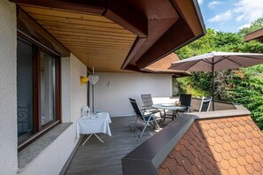 An outdoor patio with a table and chairs, a wooden ceiling, and a brick wall. - Holiday apartment with 2 bedrooms (Meersburg)