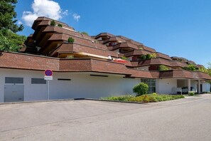 Un edifici residencial de diversos pisos amb un estil arquitectònic característic, que destaca per una sèrie de balcons i un senyal de prohibició de pàrquing.