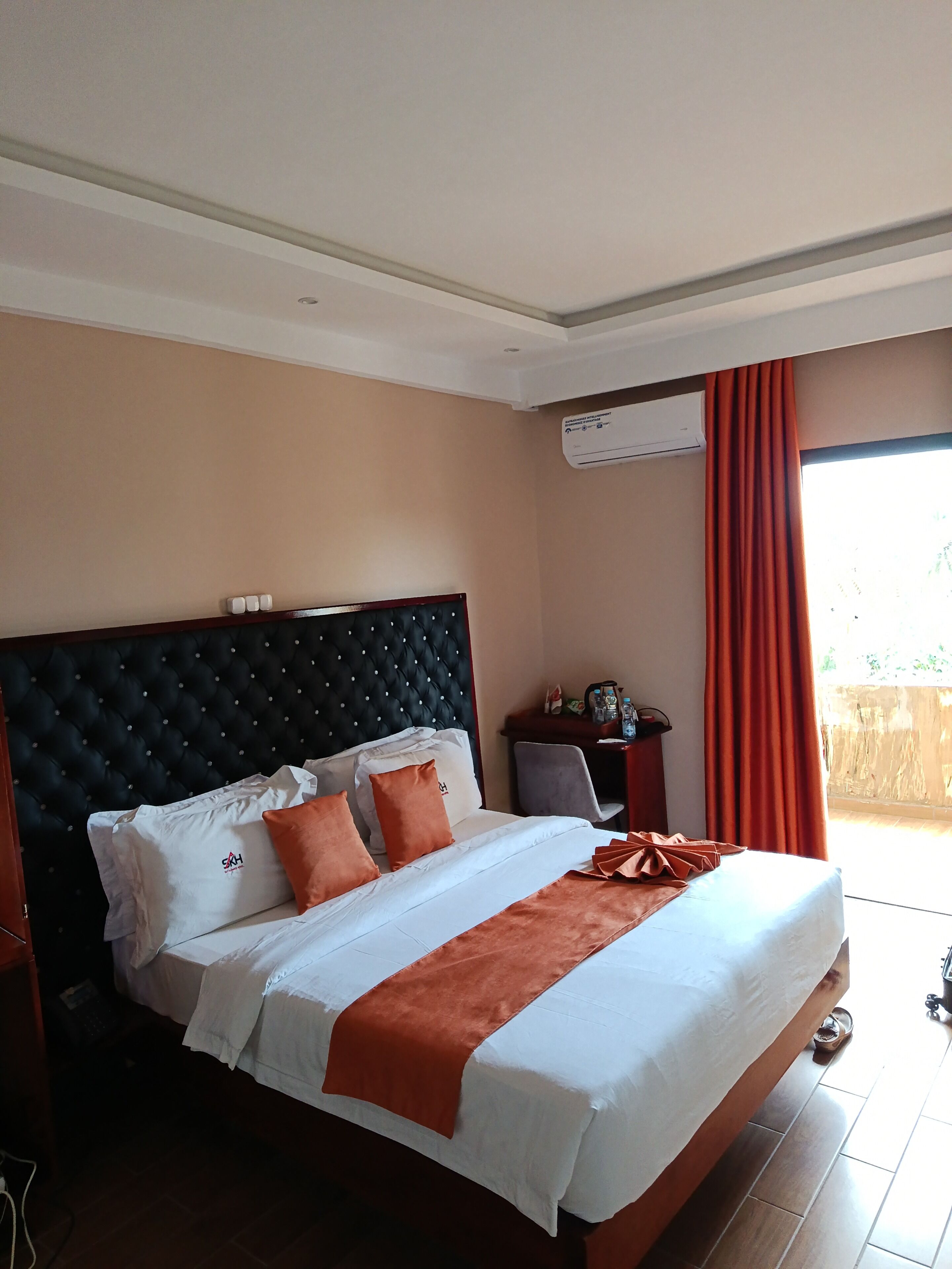 Quarto de hotel com cama grande, cabeceira, mesa de cabeceira e ar condicionado.