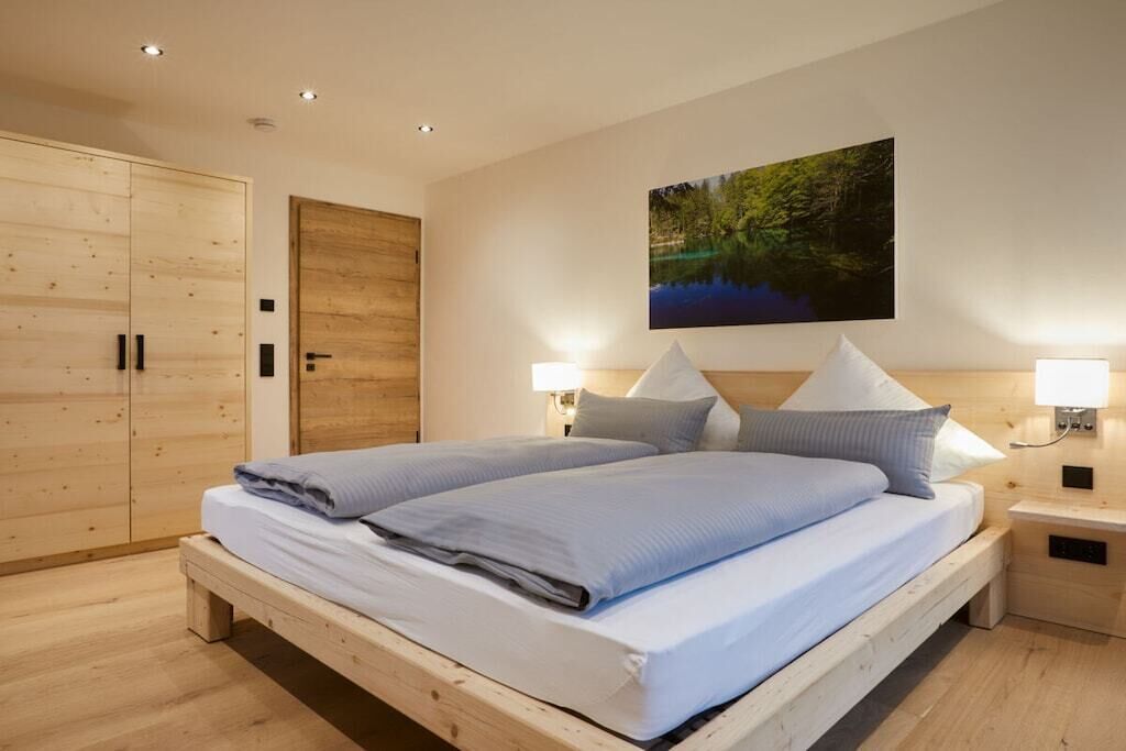 A bedroom with a wooden bed, a large wardrobe, and a painting on the wall.