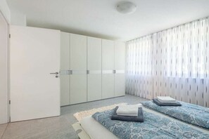 Ein Schlafzimmer mit einem Bett, einem Kleiderschrank und einem Fenster mit Vorhängen.
