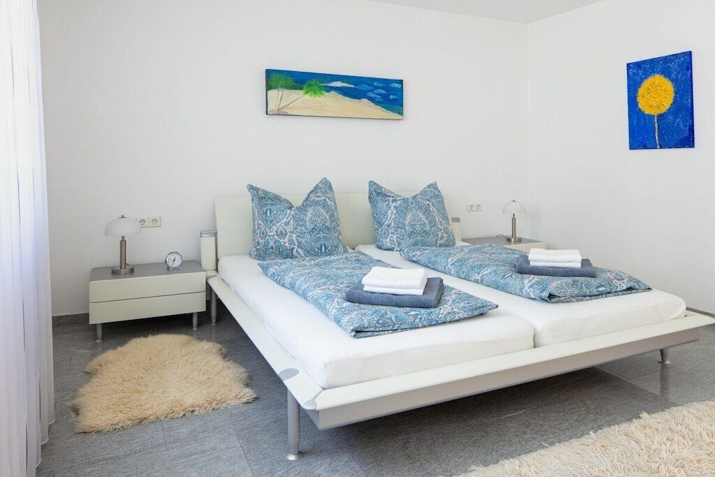 Un dormitorio con una cama, dos mesitas de noche, una lámpara de noche, una alfombra y decoración en la pared.