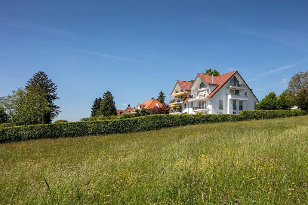 A large white house with a red roof, surrounded by a well-maintained lawn and trees.