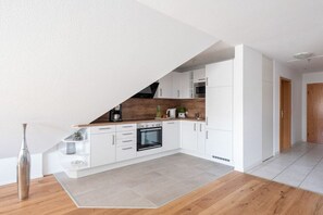 A modern kitchen with white cabinetry, a wooden countertop, and a built-in oven. - Holiday apartment with 1 bedroom (Überlingen)