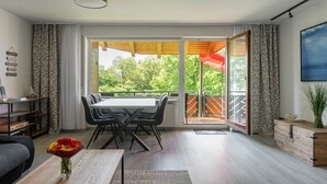 Un soggiorno moderno con zona pranzo, ampie finestre e vista sul verde.