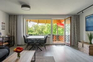 Ein modernes Wohnzimmer mit Essbereich, großen Fenstern und Blick ins Grüne.