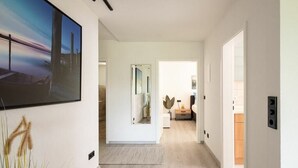 Un corridoio moderno dal design minimalista, con un grande dipinto astratto, uno specchio e un pavimento in legno.