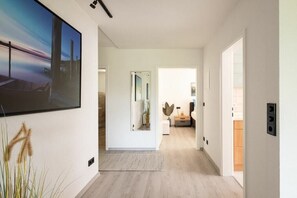 Ein moderner Flur mit minimalistischem Design, der ein großes abstraktes Gemälde, einen Spiegel und einen Holzboden zeigt.
