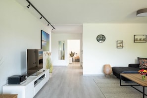 Een moderne woonkamer met een flatscreen televisie, een bank, een salontafel en een eethoek.