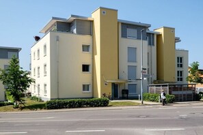 Een meerlaags woongebouw met een platte gevel, een duidelijke ingang en een fiets voor de deur.