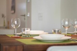 Een eettafel gedekt met borden, glazen en bestek, met een groene placemat.