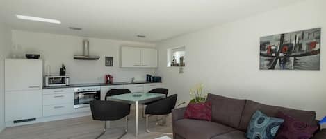 Un espacio habitable moderno con comedor, kitchenette y sofá con cojines decorativos.