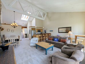 A spacious living area with a dining table, sofas, a coffee table, and a kitchen in the background. - Lake View | Top Floor | Shared Pool (Keystone)