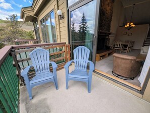 A balcony with two Adirondack chairs, a dining area with a table and chairs, and a stone fireplace. - Lake View | Top Floor | Shared Pool (Keystone)