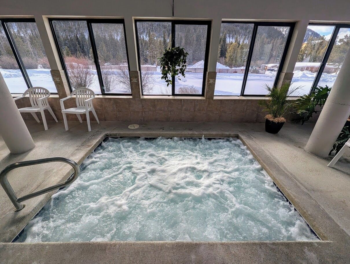 Une piscine intérieure donnant sur un paysage enneigé grâce à de grandes baies vitrées.