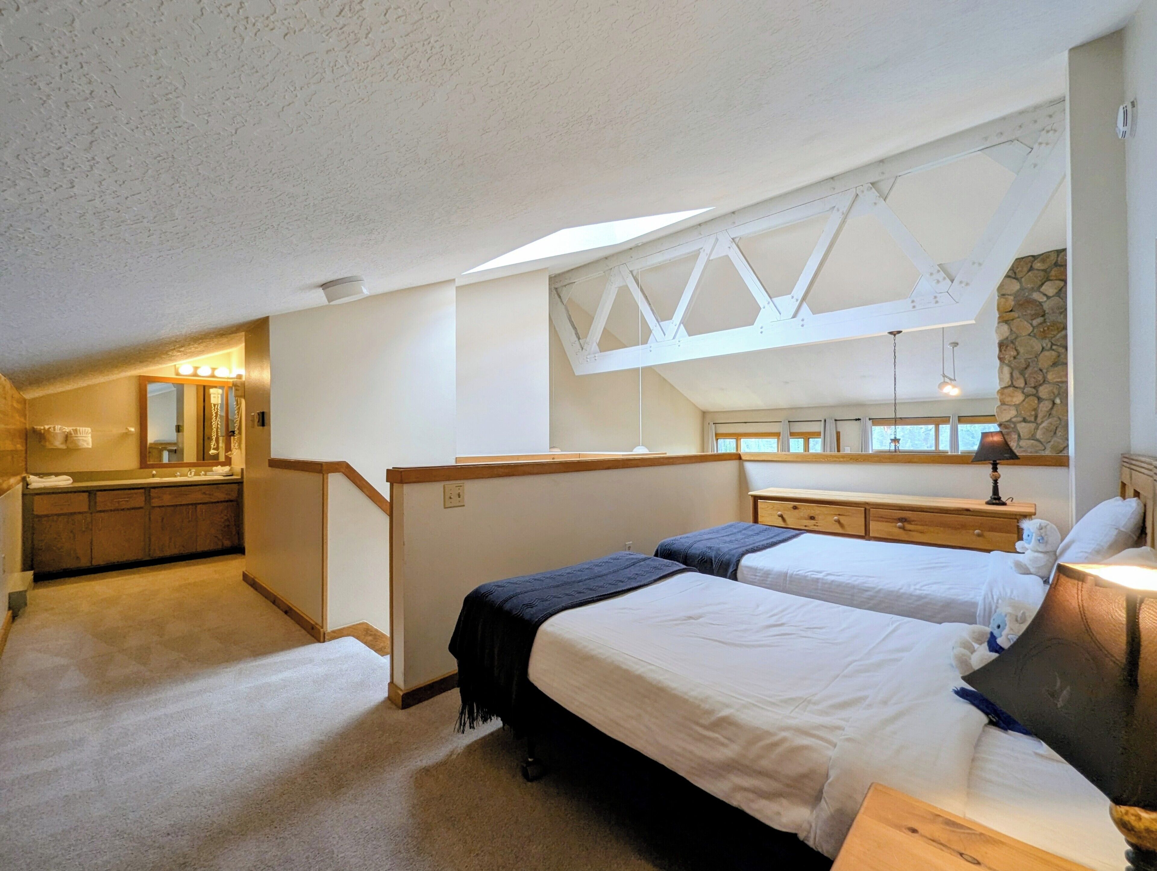 A bedroom with two beds, a bathroom with a vanity, and a skylight.