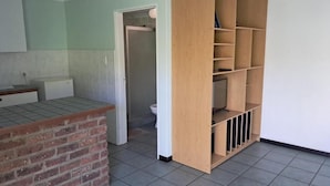 Um quarto com balcão de tijolos, prateleiras de madeira e chão ladrilhado.