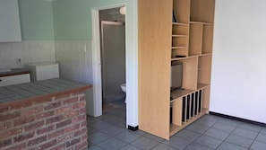 A room with a brick counter, a wooden shelving unit, and a tiled floor. - Room-thornycroft Lodge & Spa Kugompo Cit (East London)