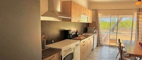 A kitchen with a stove, oven, and a dining area with a table and chairs.