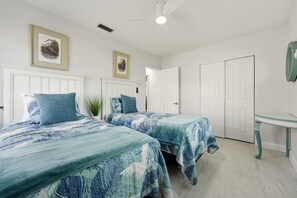 A bedroom with two beds, a ceiling fan, and a small table. - Venice Island Florida pool Home (Venice)