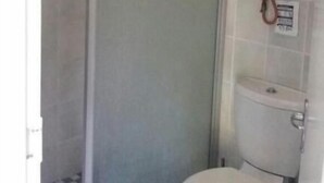 Casa de banho com sanita, cabine de duche e aquecedor fixo à parede.