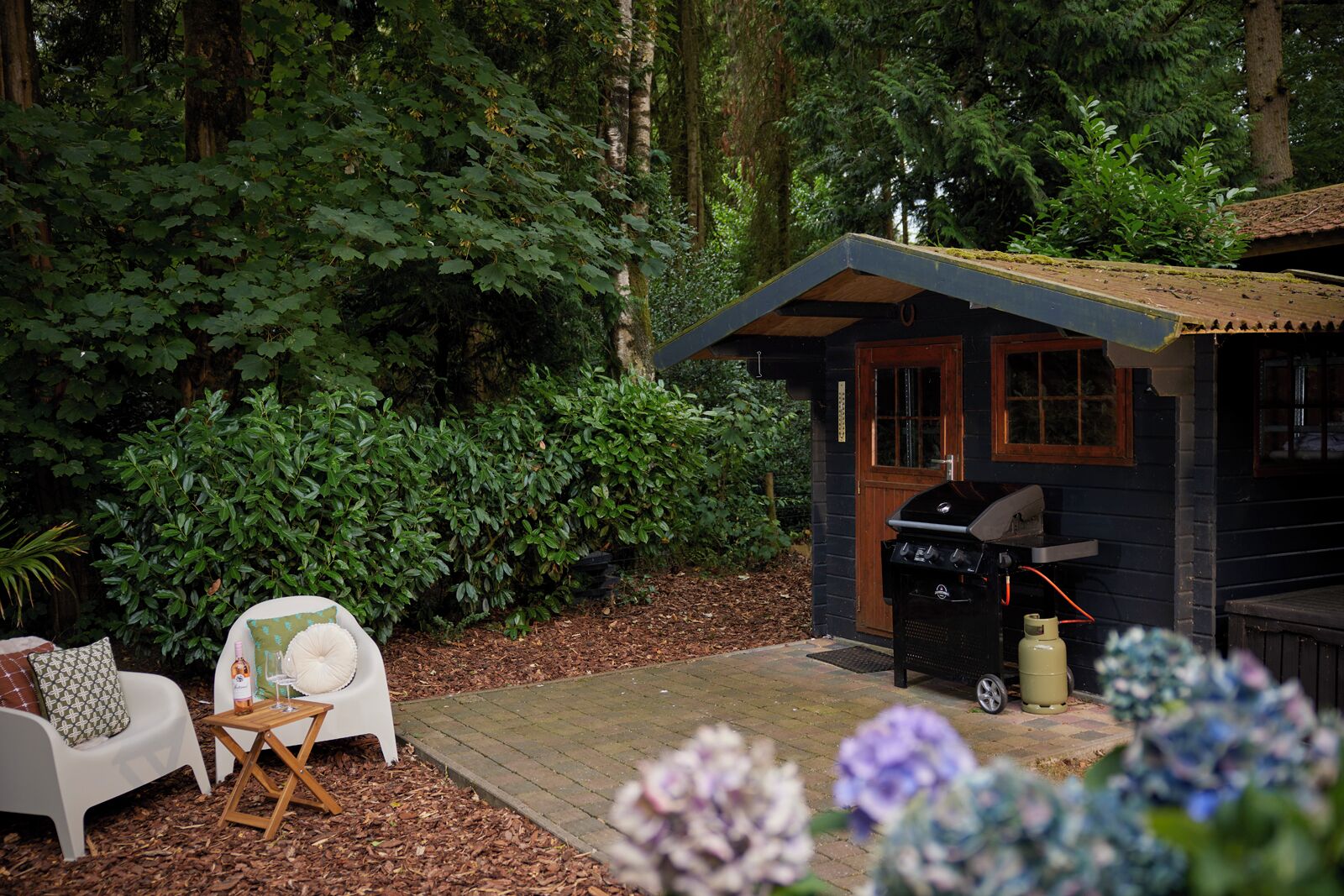 A wooden deck with a barbecue grill, a white chair, and a small table.