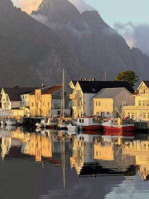 En hamn med båtar, byggnader och berg i bakgrunden.