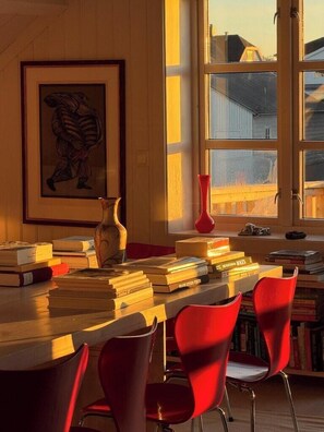 A room with a wooden desk, books, a vase, and a red chair. - Top-floor flat by the harbour in Henningsvær (Henningsvær)