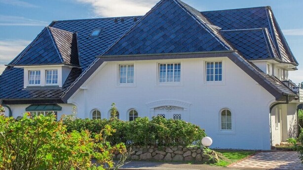 Um edifício grande e branco, com telhado inclinado e várias janelas.